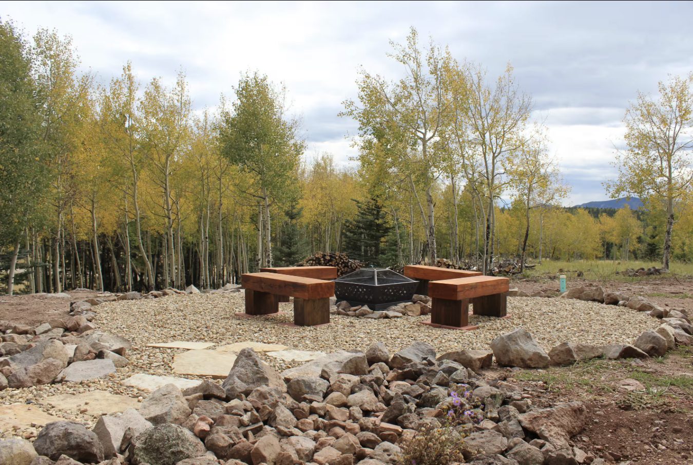 Outdoor fire pit surrounded by aspens